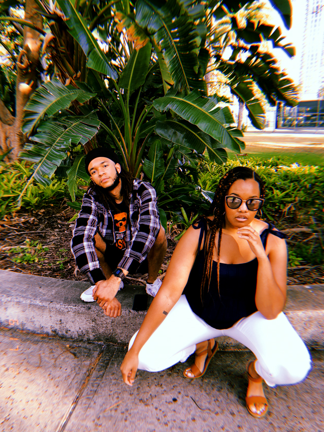 black girl and boy squatting in front of Hawaiian nature and landscape