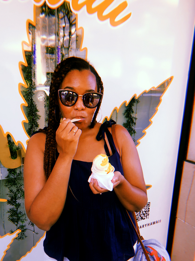 black girl eating dole whip in front of Hawaiian cbd store